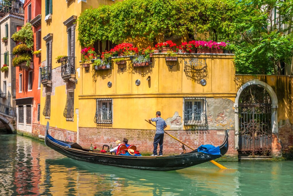 Ein Paar wird in einer traditionellen Gondel durch einen Kanal in Venedig gefahren