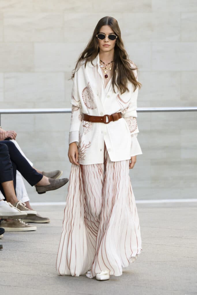 Marc Cain Frühjahr Sommer 2026 Kollektion – weisses Maxi-Ensemble mit Korallen-Print, braunem Ledergürtel und ovaler Sonnenbrille, Berlin Fashion Week