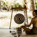 Klangschalenmeditation im Varua Te Ora Polynesian Spa des The Brando Resorts auf Tetiaroa – eine Therapeutin spielt tibetische Klangschalen und einen Gong in einem offenen Pavillon unter Palmen