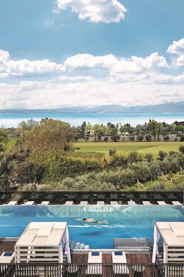 Schönste Hotelpools 2026: 6 spektakuläre Luxus-Pools für den Sommer Ein Schwimmer zieht im Skypool des Quellenhof Luxury Resort Lazise seine Bahnen mit weitem Blick über die mediterrane Landschaft auf den Gardasee.