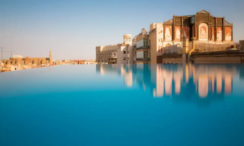 Historische Architektur aus dem Jahr 1926 trifft auf den modernen Infinity Pool an der Via Laietana. (Quelle: Grand Hotel Central Barcelona)