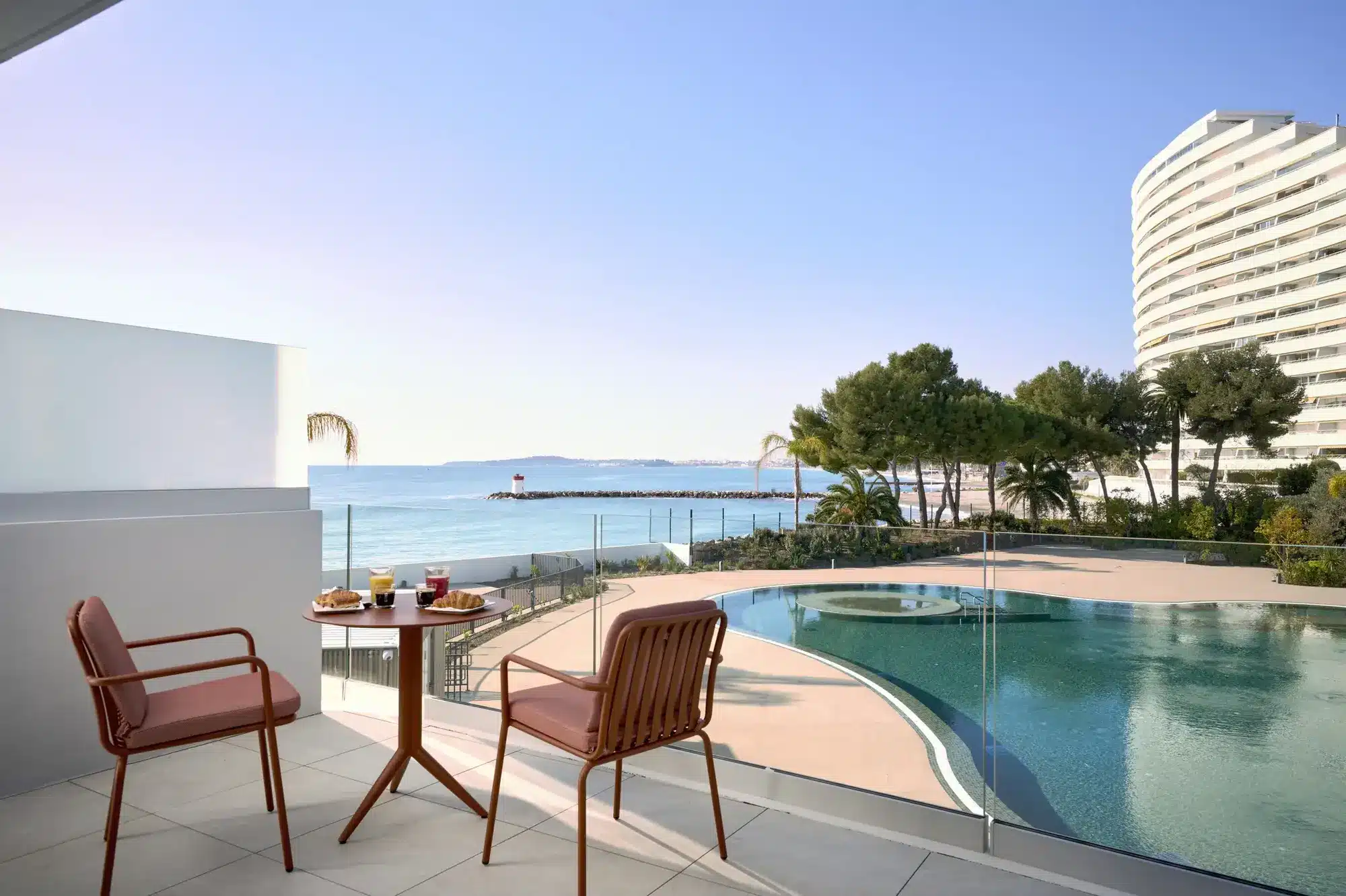 Marina Baie des Anges Hotel: Neue Riviera-Ikone mit 61 Zimmern Terrasse des Marina Baie des Anges Hotel mit Blick auf die geschwungenen Kurven der Marina von André Minangoy. (Quelle: © 2026 Hilton)