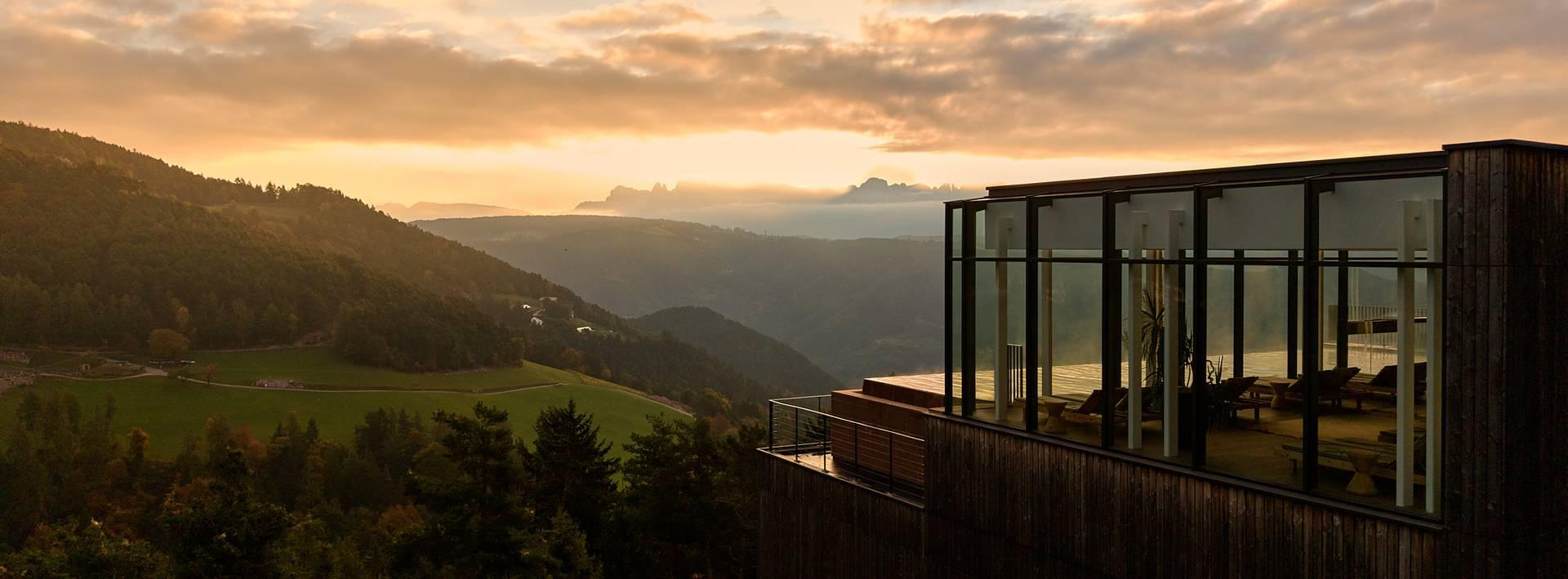 Longevity Retreat Südtirol: Hotel Saltus in Jenesien mit Panoramafenstern über dem Etschtal und den Dolomiten im Abendlicht